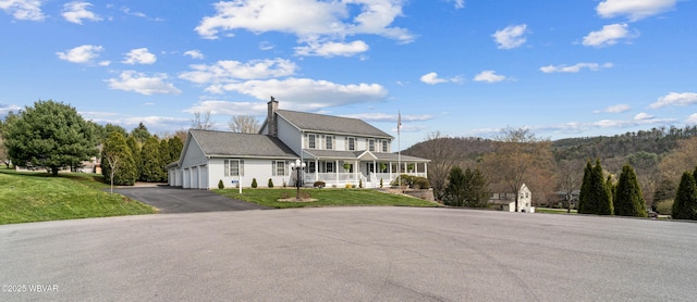 view of front of home featuring a porch, a front lawn, asphalt driveway, and a garage