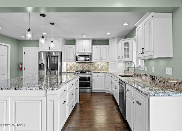 kitchen with appliances with stainless steel finishes, a sink, white cabinets, recessed lighting, and light stone countertops