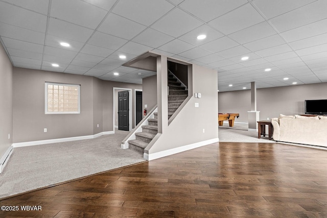 finished below grade area featuring baseboards, pool table, stairs, wood-type flooring, and a paneled ceiling