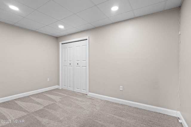 unfurnished bedroom featuring carpet floors, baseboards, recessed lighting, a closet, and a drop ceiling