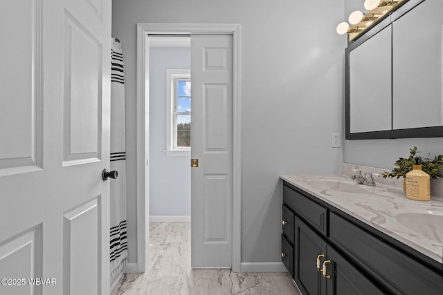 bathroom featuring marble look tile flooring, double vanity, and baseboards