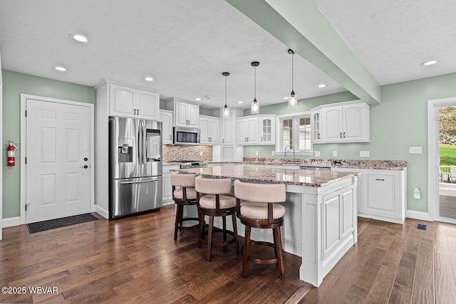 kitchen featuring appliances with stainless steel finishes, white cabinetry, dark wood-style floors, recessed lighting, and a center island