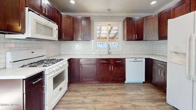 kitchen with tasteful backsplash, white appliances, sink, and hanging light fixtures