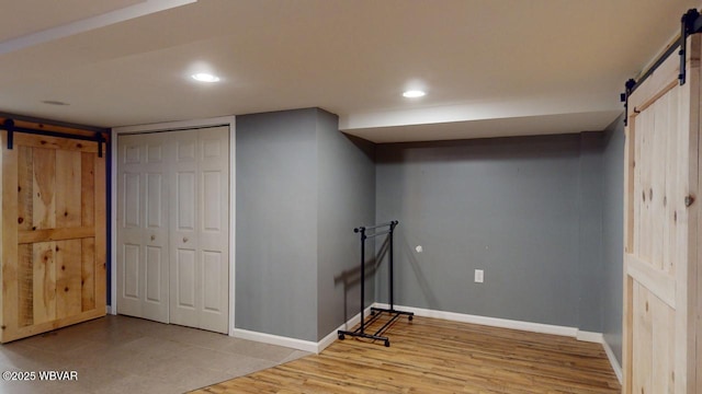 basement with a barn door and light hardwood / wood-style floors