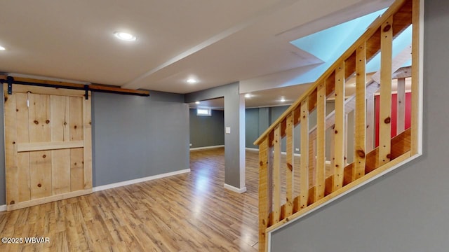 basement featuring hardwood / wood-style flooring and a barn door