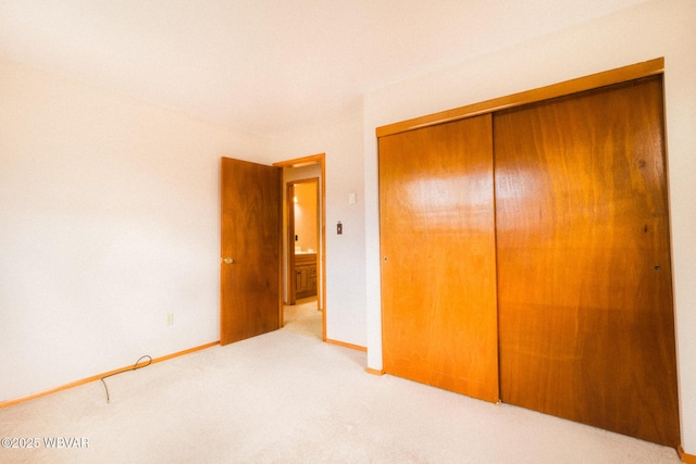 unfurnished bedroom with light colored carpet and a closet