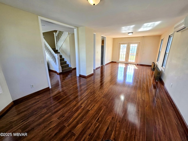 unfurnished living room featuring baseboards, a wall mounted air conditioner, stairway, and dark wood finished floors