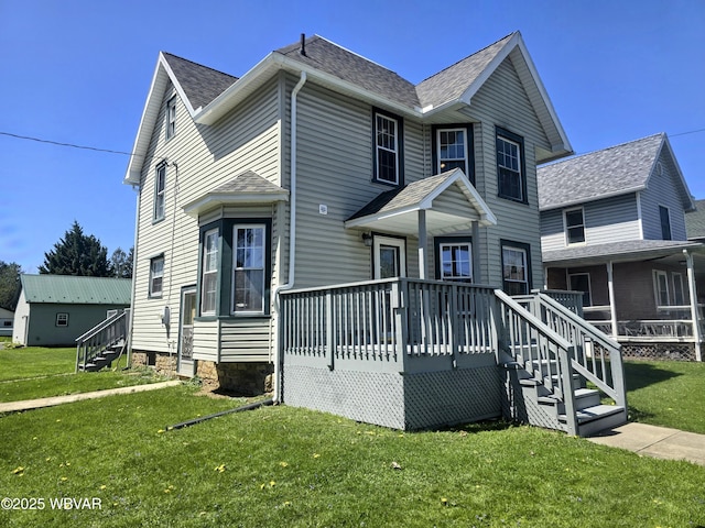 view of front of property with a front yard, a wooden deck, and roof with shingles