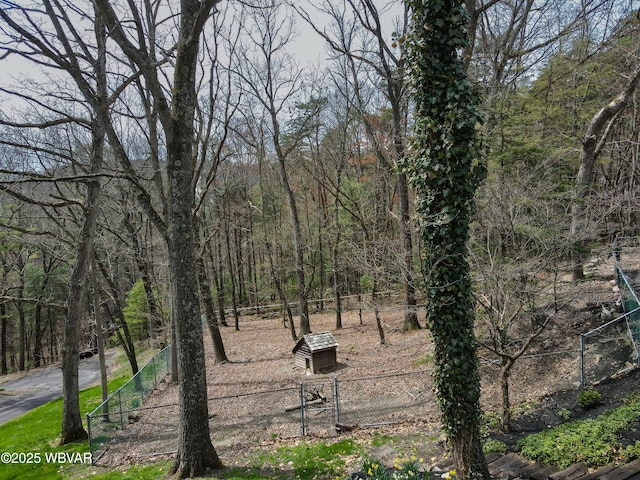 view of yard featuring a forest view and fence