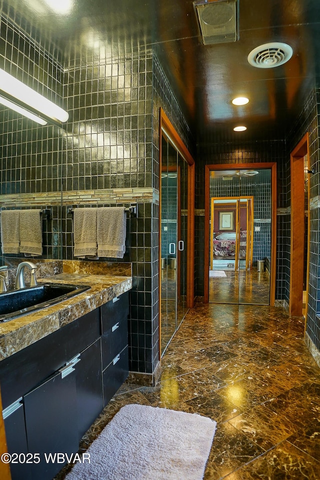 bathroom with tile walls, visible vents, and marble finish floor