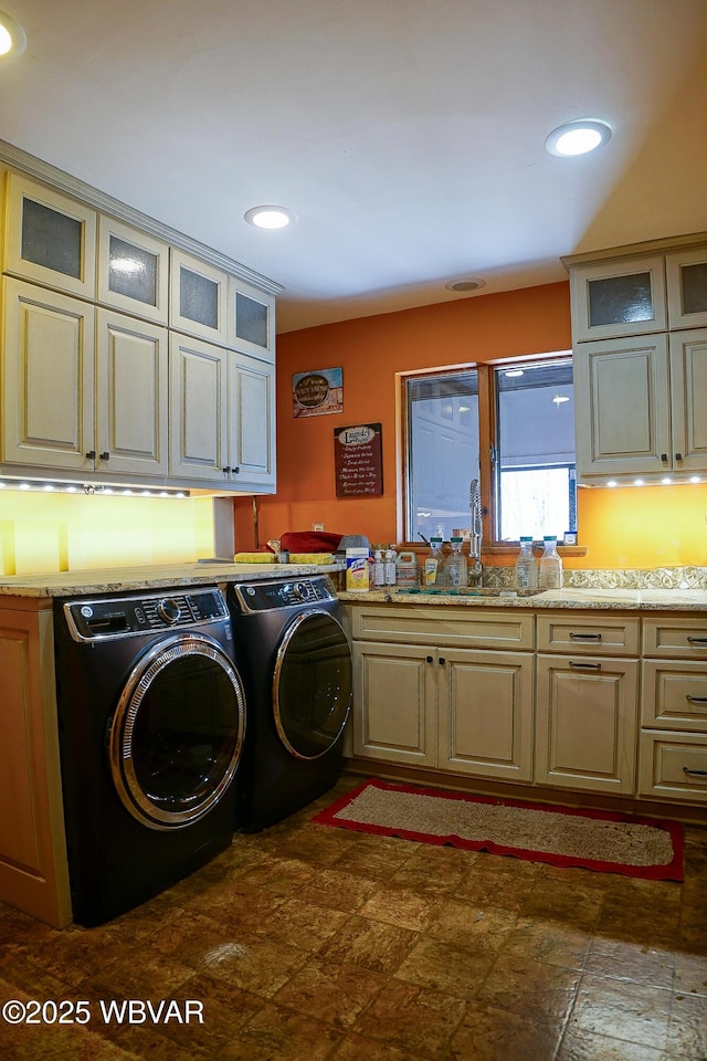 clothes washing area featuring recessed lighting, a sink, washing machine and dryer, stone finish flooring, and cabinet space