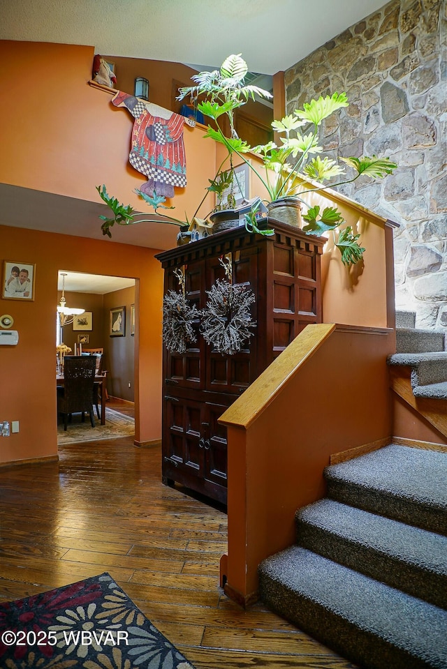 stairway with a notable chandelier and wood-type flooring