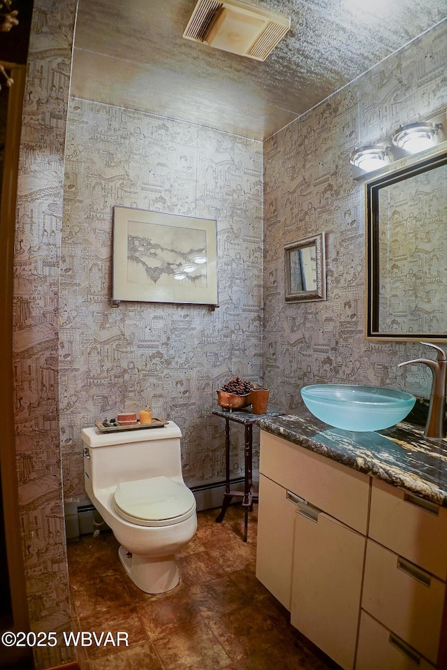 half bath featuring baseboard heating, toilet, vanity, and visible vents