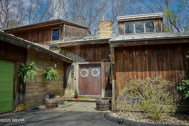 property entrance with a chimney and stone siding