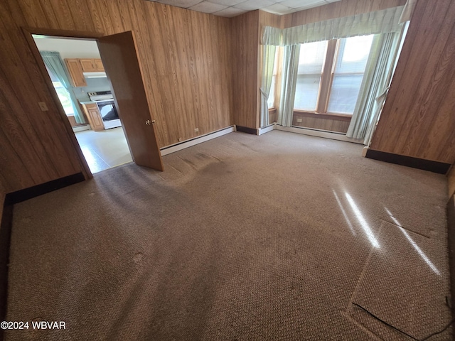 carpeted empty room with wood walls and a baseboard radiator