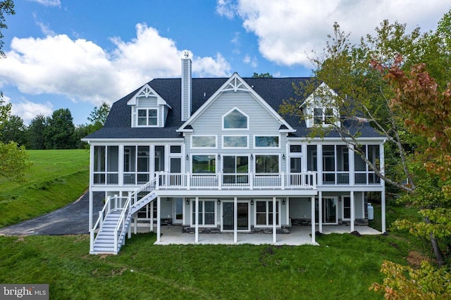 rear view of property with a patio area, a sunroom, and a lawn