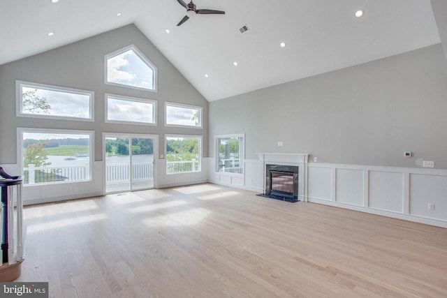 unfurnished living room featuring plenty of natural light, high vaulted ceiling, and light hardwood / wood-style flooring