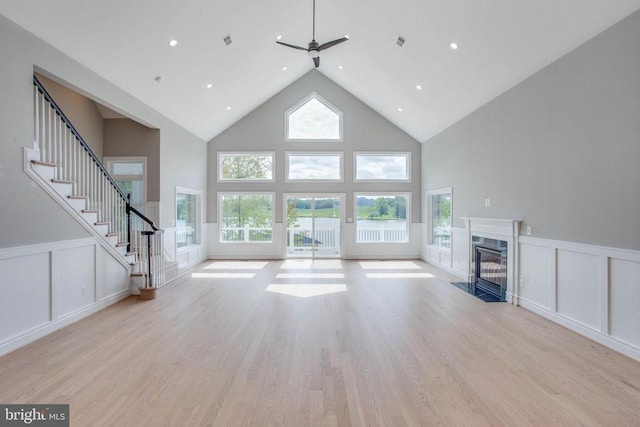 unfurnished living room featuring high vaulted ceiling, light hardwood / wood-style floors, and ceiling fan