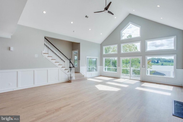 unfurnished living room featuring plenty of natural light, ceiling fan, high vaulted ceiling, and light wood-type flooring