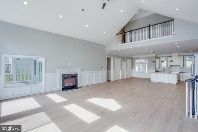 unfurnished living room featuring high vaulted ceiling, light hardwood / wood-style floors, ceiling fan, and a fireplace