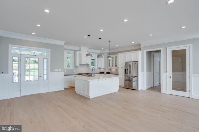 kitchen featuring white cabinets, stainless steel fridge with ice dispenser, light wood-type flooring, and a center island