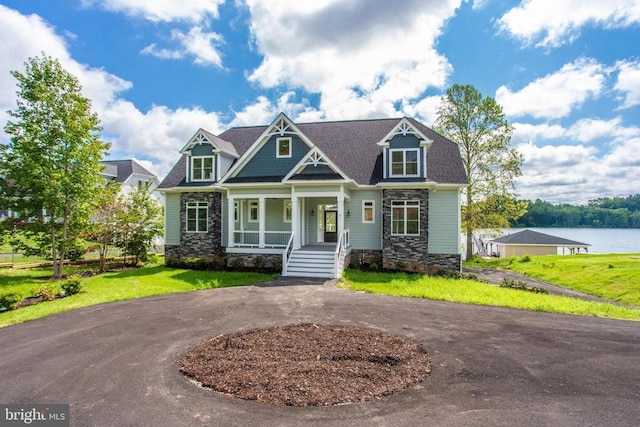 craftsman inspired home featuring a porch, a water view, and a front yard