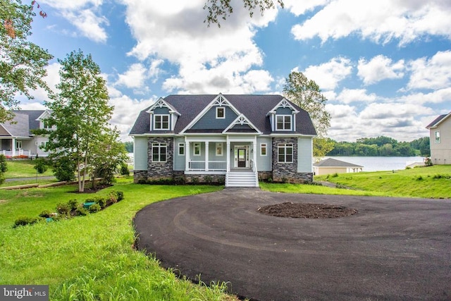 craftsman-style house featuring a water view, covered porch, and a front lawn