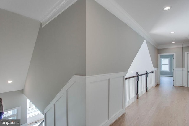 corridor with light hardwood / wood-style flooring and ornamental molding