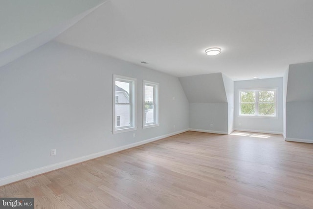 additional living space featuring light wood-type flooring and vaulted ceiling