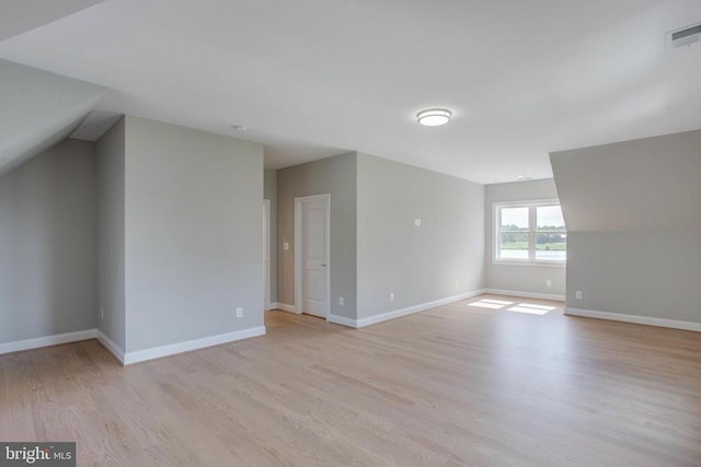 unfurnished room with lofted ceiling and light hardwood / wood-style floors