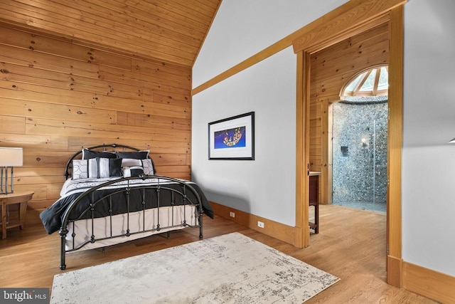 bedroom with lofted ceiling, ensuite bath, light hardwood / wood-style flooring, and wood walls