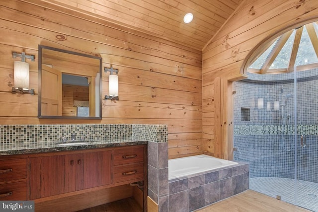 bathroom featuring tiled tub, vaulted ceiling, wood walls, and hardwood / wood-style flooring