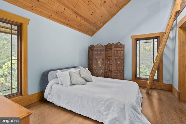 bedroom with multiple windows, vaulted ceiling, wooden ceiling, and light hardwood / wood-style flooring