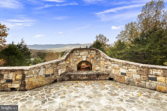 view of patio / terrace with a mountain view and an outdoor stone fireplace