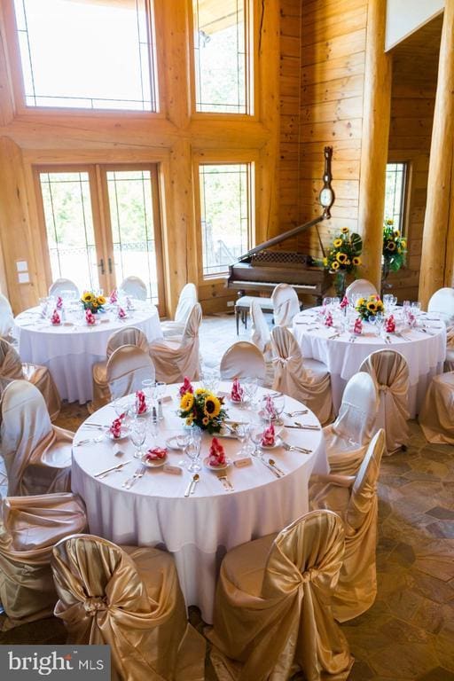 dining space with wooden walls, a high ceiling, and french doors