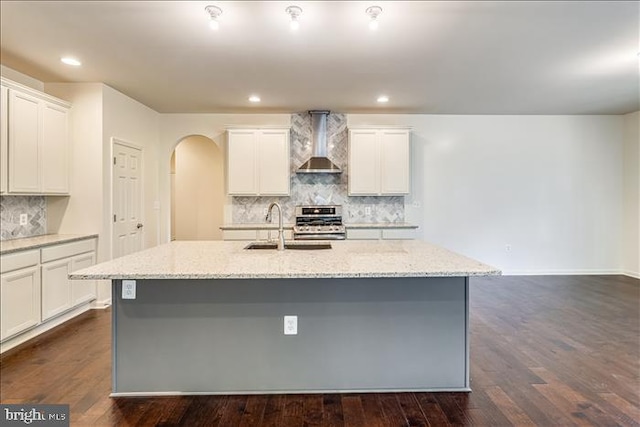 kitchen with dark hardwood / wood-style floors, an island with sink, tasteful backsplash, and wall chimney exhaust hood