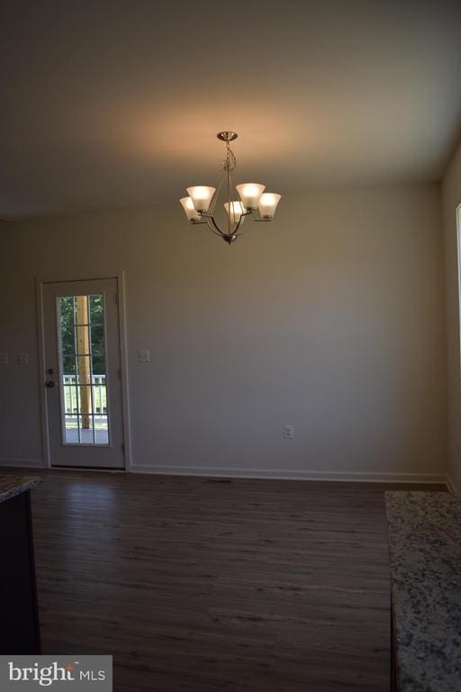 spare room with dark hardwood / wood-style flooring and a chandelier