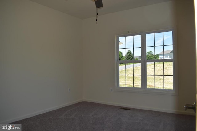 unfurnished room with ceiling fan and dark carpet