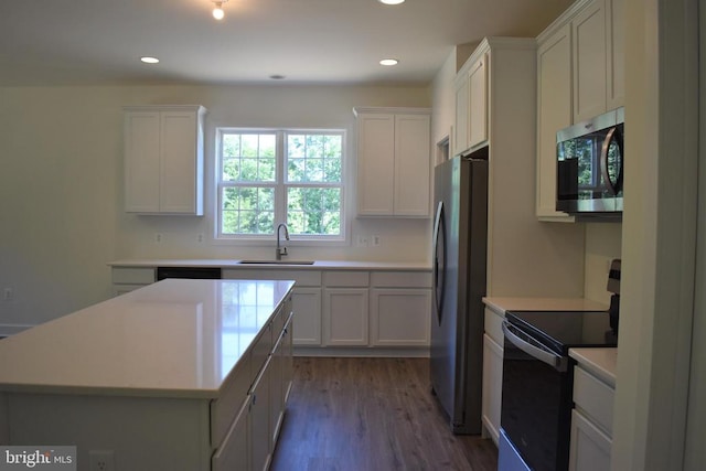 kitchen featuring appliances with stainless steel finishes, a center island, hardwood / wood-style floors, sink, and white cabinets