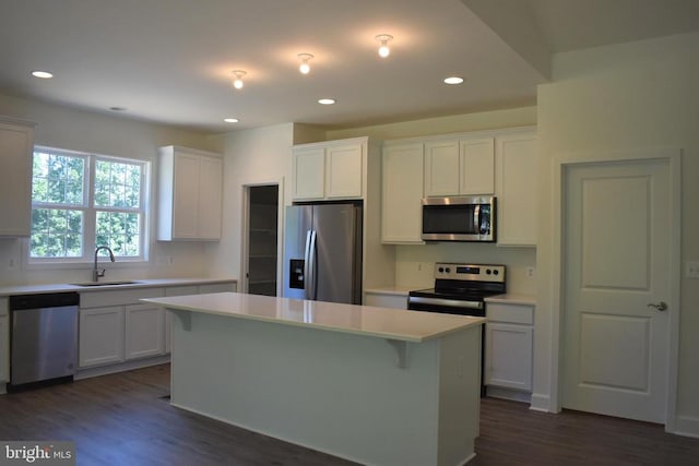 kitchen featuring stainless steel appliances, a kitchen island, dark wood-type flooring, white cabinets, and sink