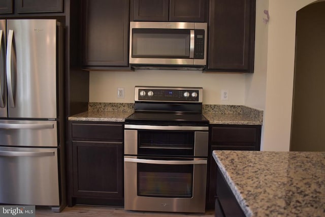 kitchen featuring light hardwood / wood-style floors, dark brown cabinetry, stainless steel appliances, and light stone counters