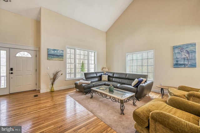 living room with high vaulted ceiling and light hardwood / wood-style flooring