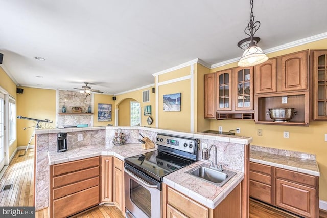 kitchen with light hardwood / wood-style floors, stainless steel range with electric stovetop, pendant lighting, ceiling fan, and sink