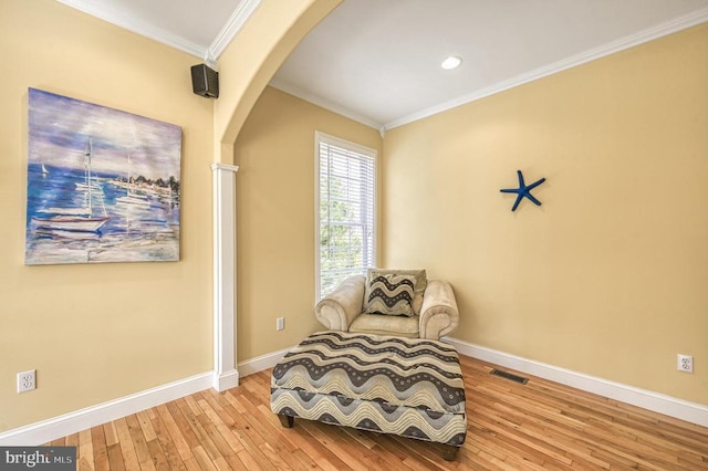 living area with ornamental molding and light hardwood / wood-style flooring