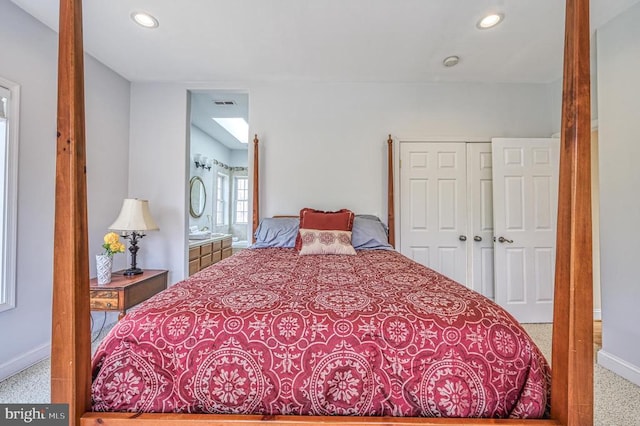 bedroom with light colored carpet, ensuite bathroom, and a closet