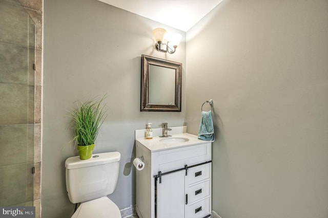 bathroom with toilet, a tile shower, and vanity