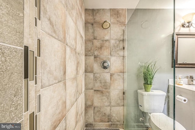 bathroom featuring toilet, a tile shower, and vanity