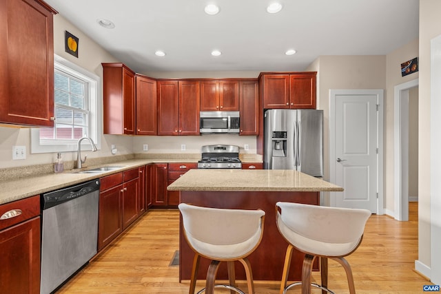 kitchen featuring a sink, stainless steel appliances, dark brown cabinets, light wood-style floors, and a center island