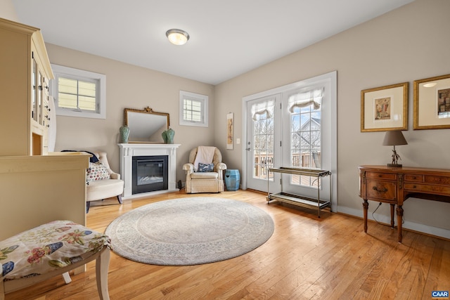 foyer entrance featuring a glass covered fireplace, baseboards, and light wood-type flooring