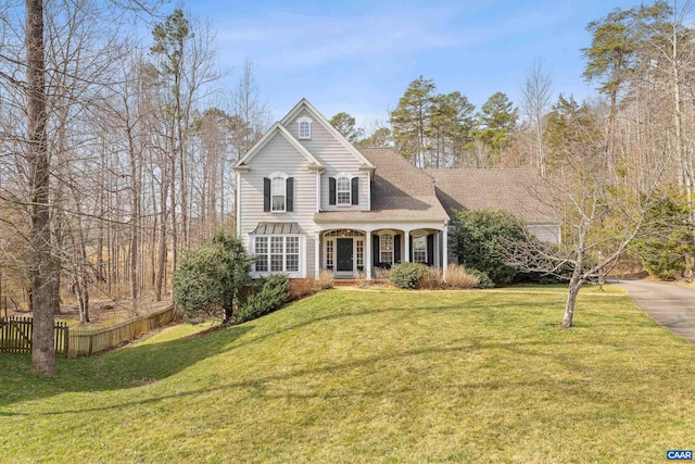 traditional-style house with a front yard, a porch, and fence